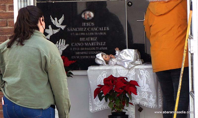 Una joven observa la imagen de un Niño en el panteón de su familia