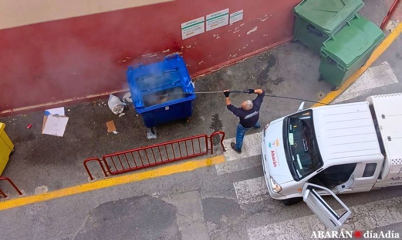 Un operario municipal sofoca el incendio declarado en un contenedor de papel y cartón